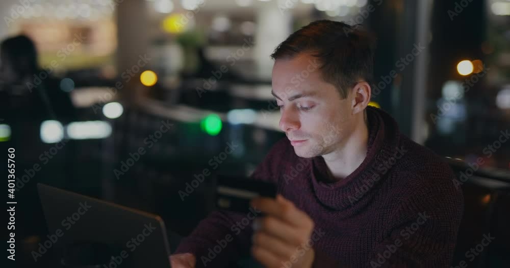Credit card in male hand, man shopping online at the night time Credit card in male hand, man shopping online at the night time