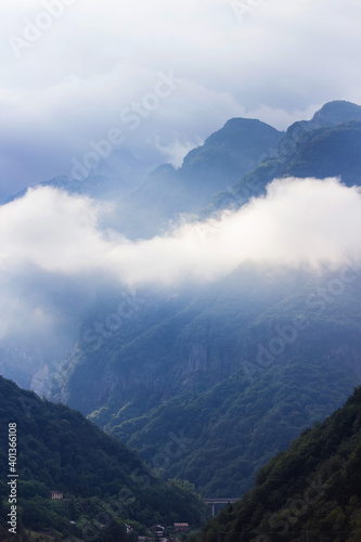 Beautiful Alpine mountainous scenery on the road to the city of Siena, Tuscany, Italy. Alps mountains on cloudy and foggy day. Soft selective focus, long exposure