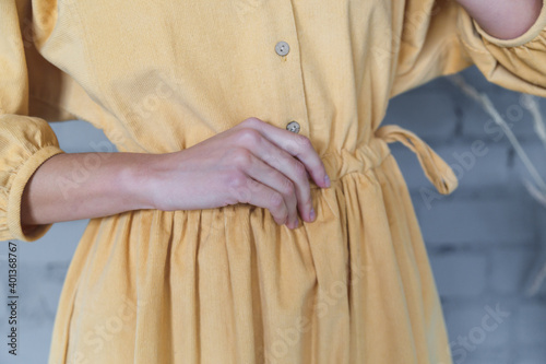 beautiful yellow corduroy dress on a girl close-up. Hand on the belt