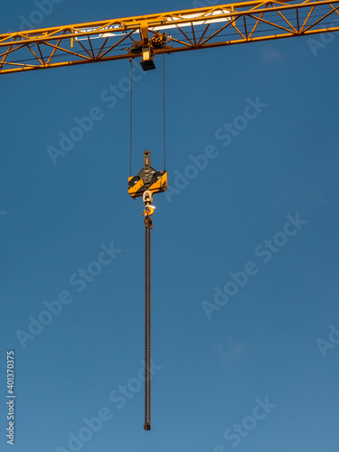 Crane girder with hanging chain on blue sky background