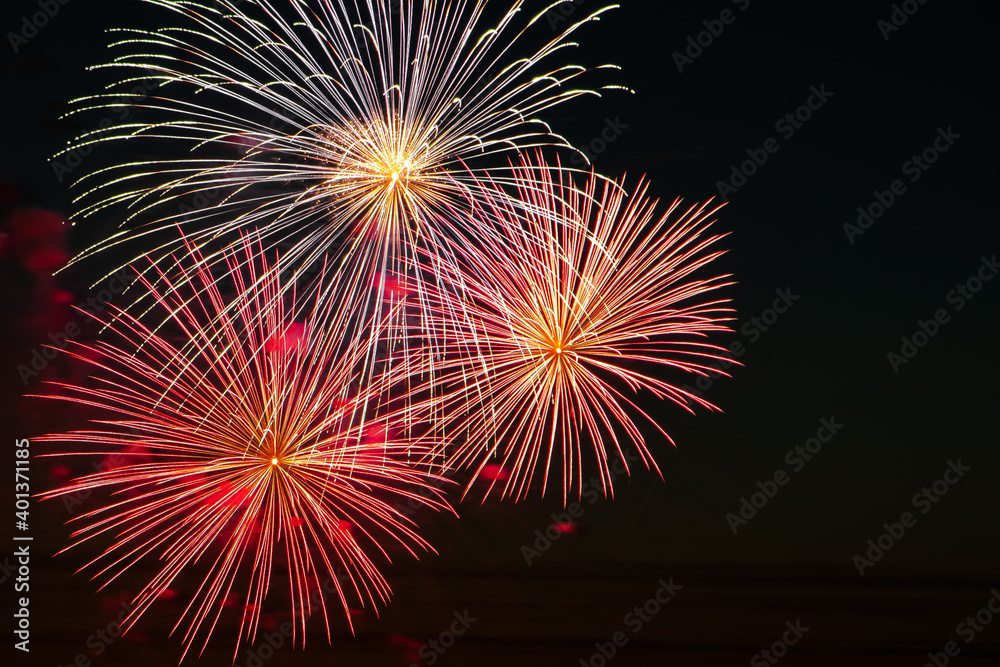 Festive fireworks in the sky for a holiday. Bright multi-colored salute on a black background. Place for text.