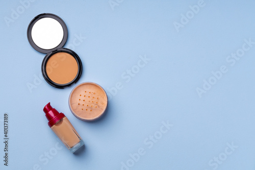 Complexion make up products and brush on blue background