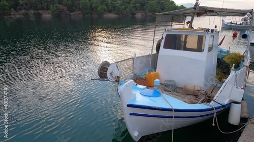 Greek traditional wooden fishing boat in the harbour at dusk photo