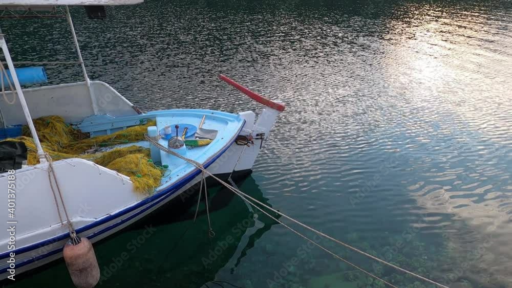 Greek traditional wooden fishing boat in the harbour at dusk