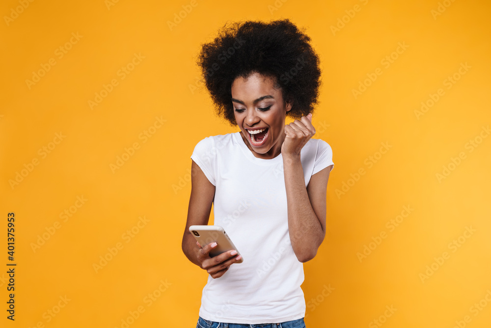 Happy young african american woman rejoicing while holding cellphone