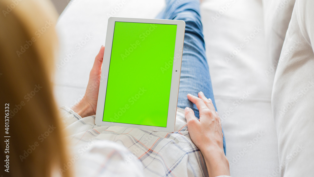 young woman is relaxing on comfortable couch and using tablet at home young woman is relaxing on comfortable couch and using tablet at home