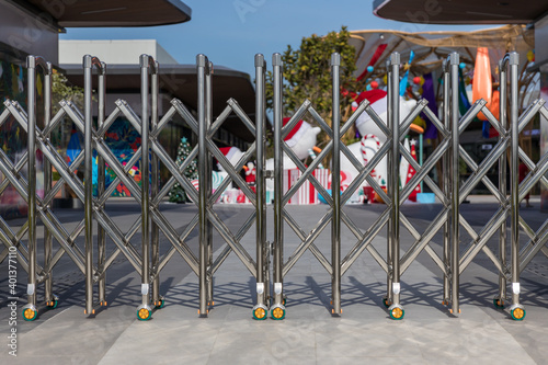 Folding retractable fence on casters.  barrier on casters. Sliding gates on rollers. Pedestrian barrier. Barricade Gate. Lockdown and protection concept flu Covid-19 or coronavirus