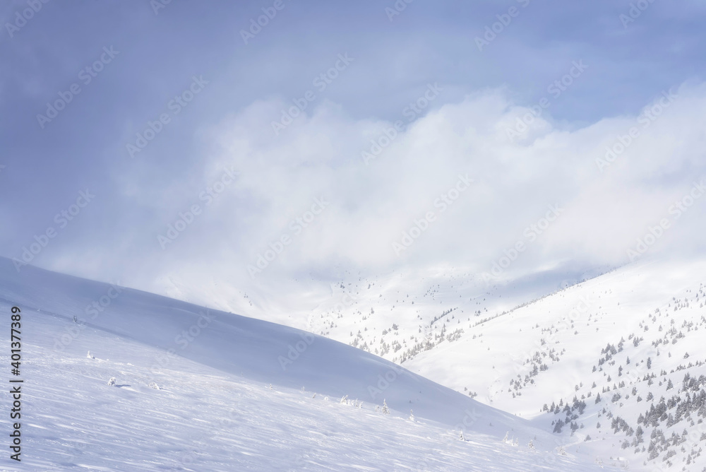 Clouds covering the snowy mountain slope. Winter landscape.