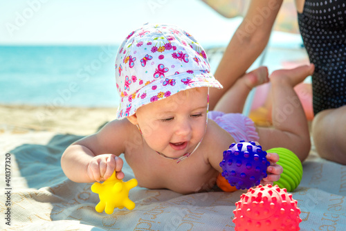 an adorable child on the beach plays with educational bright toys. Holidays with children at sea.