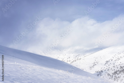 Clouds covering the snowy mountain slope. Winter landscape.