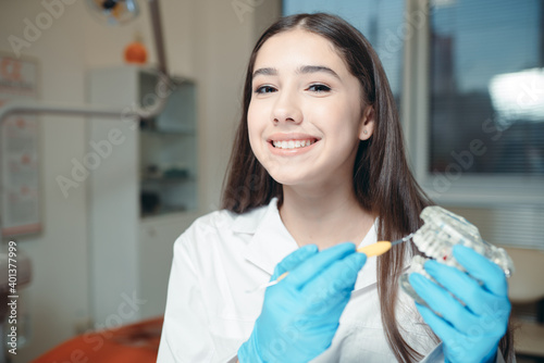 Beautiful girl smiles at the camera and holds a model of teeth. Healthy smile