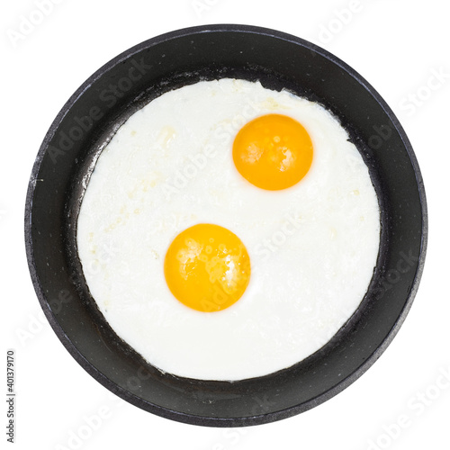 top view of fried eggs in black round pan isolated