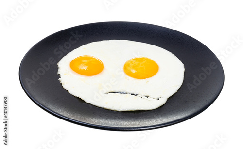 two fried eggs on black plate isolated on white background. Fried eggs like the angry face