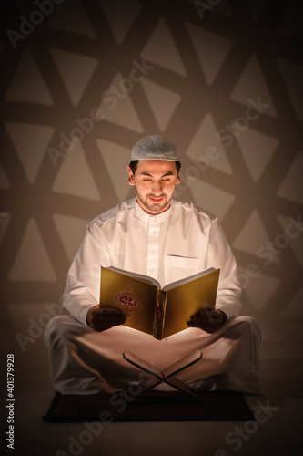 islam religion background of muslim man holding holy quran book reading and study quran book in dark room photo