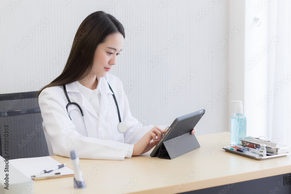 Coronavirus protection concept. Serious professional doctor wearing white coat and stethoscope holding modern touchscreen gadget using digital tablet computer at work. Coronavirus protection concept. Serious professional doctor wearing white coat and stethoscope holding modern touchscreen gadget using digital tablet computer at work.