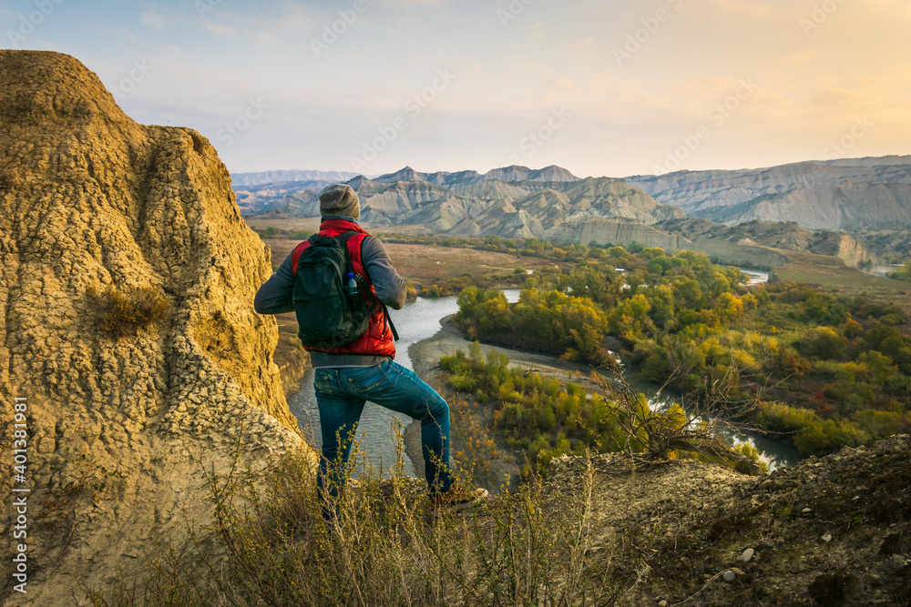 Naklejka premium Back side of Backpacker standing on the hilland looking to rocky landscape of Vashlovani nature reserve