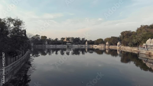 Shore view of lake Pichola Ascending to Ambrai Ghat and revealing the surrounding Old town, in Udaipur, Rajasthan, India - Aerial ascending Fly-over reveal shot photo