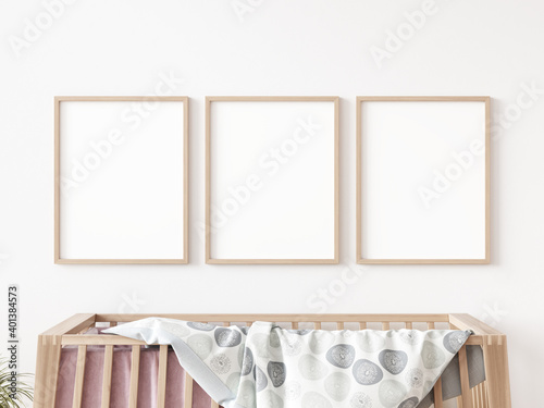 Three empty rectangular picture frames with thin wooden border hanging on white wall above cot in kids room. 3D illustration. photo