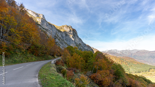 a road in Pyrenee mountains with orange autumn woods in France