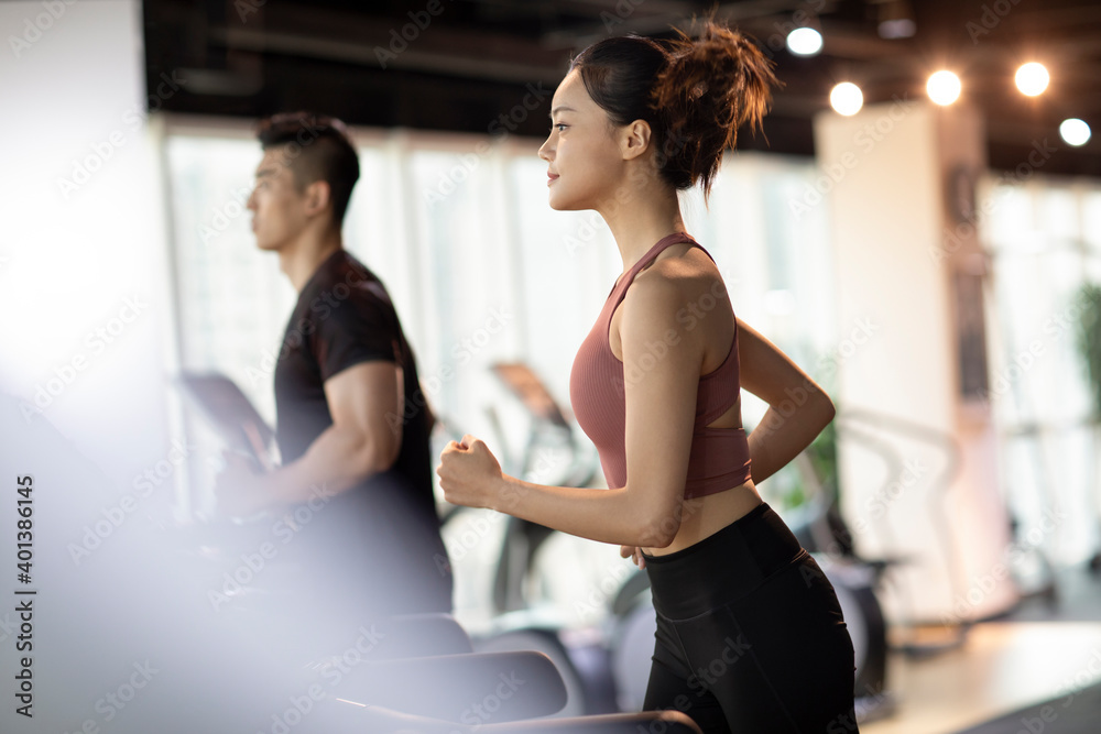 Young couple running on treadmill at gym Young couple running on treadmill at gym