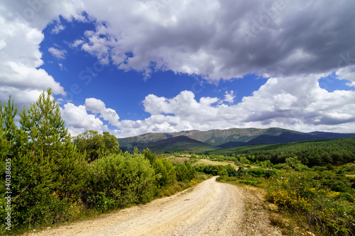 Cloudscape on the mountain. Blue sky with clouds and dirt road to the mountain. 