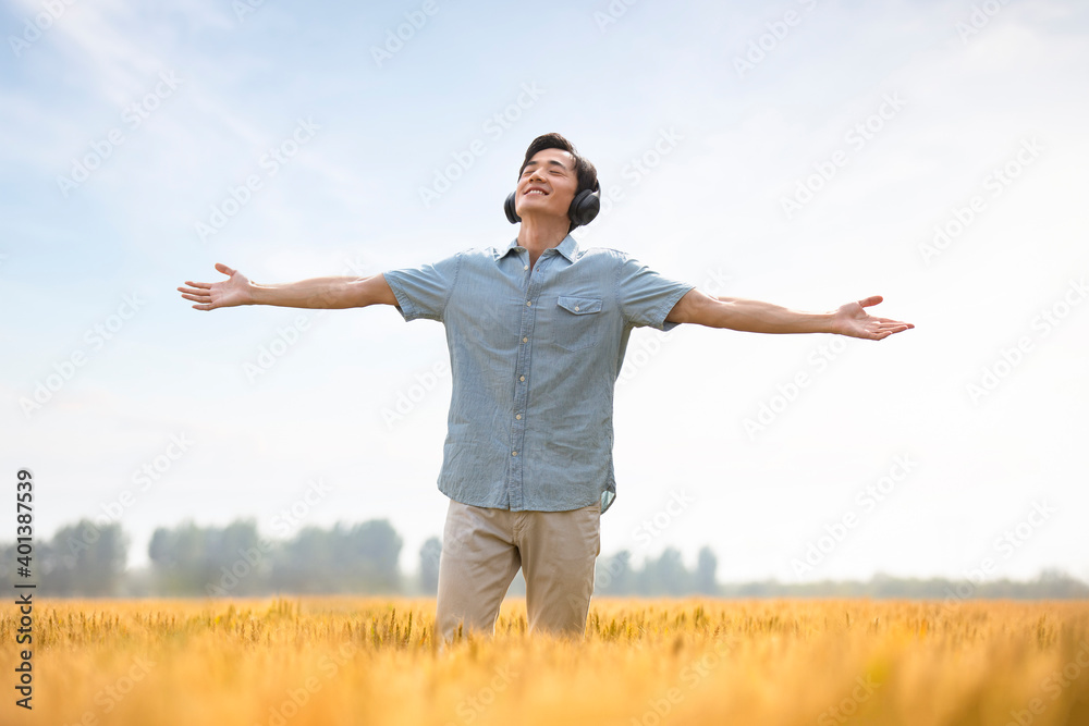 Happy young man wearing headphones in wheat field Happy young man wearing headphones in wheat field