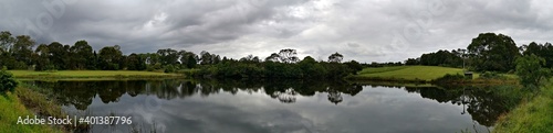 Beautiful panoramic morning view of a pond with reflections of trees and dark clouds on water  Fagan park  Galston  Sydney  New South Wales  Australia 