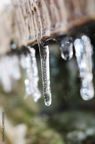 Icicles. The wooden board is frozen over. A rock. Selective focus.