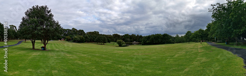 Beautiful panoramic morning view of a park with green grass, tall trees and dark cloudy sky, Fagan park, Galston, Sydney, New South Wales, Australia 
