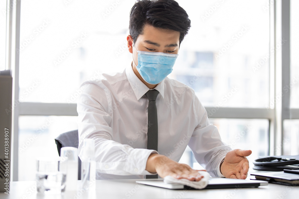 Young businessman using disinfectant in office