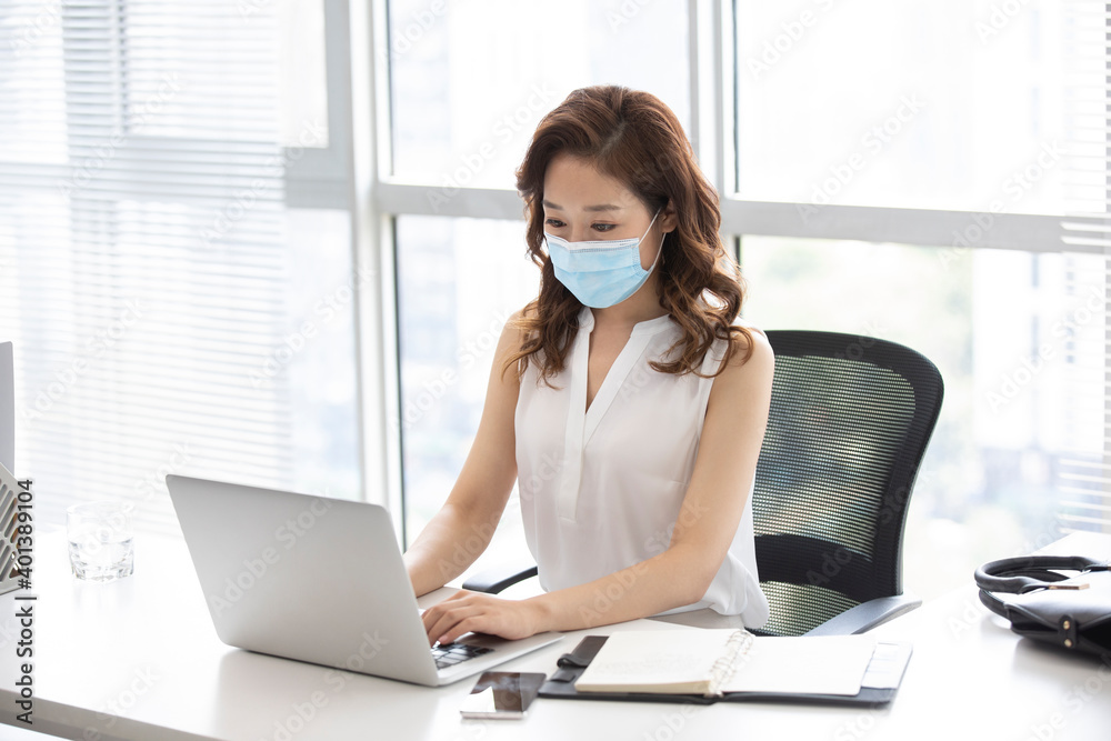 Young businesswoman with surgical mask working in office Young businesswoman with surgical mask working in office