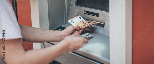 Man hand taking money from bank cash ATM machine