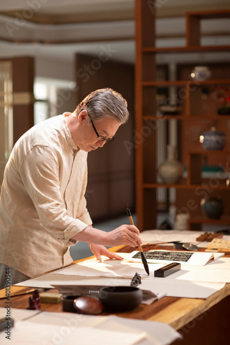 Senior man practicing calligraphy in the study photo