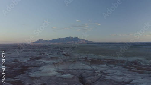 Drone footage of Mars landscape in Utah, USA during sunset blue hour with Mt Ellen Peak in the far background and few clouds in the sky. Camera dolly backwards