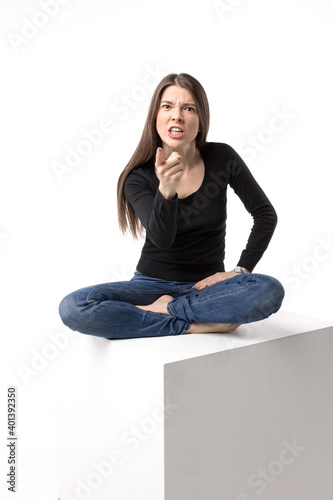 Attractive band angry brunette use threats to a camera. Isolated image on the white background.