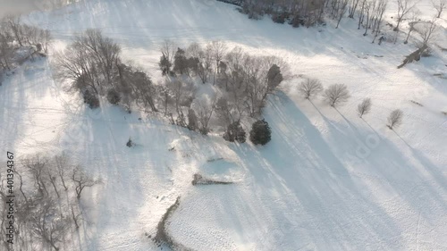 Drone video footage reveals sledders traipsing through the snow on a post-blizzard golf course, with fir trees and course features in view.