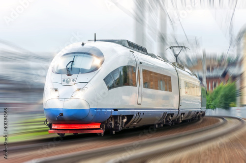 High-speed train with headlights on is driving through a corner at fast speed.