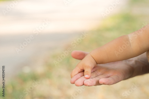 a parent holds the hand of a small child on nature background © Nastya