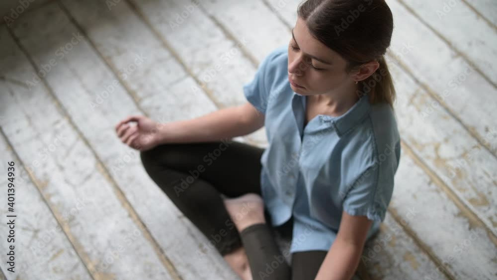 Young woman meditating sitting on the floor in an empty construction apartment, top view Young woman meditating sitting on the floor in an empty construction apartment, top view
