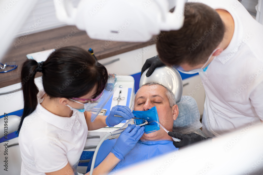 View from above at the patient sitting in a dental chair. Dentists treating tooth View from above at the patient sitting in a dental chair. Dentists treating tooth