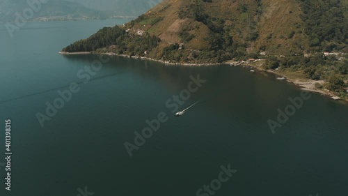 Drone aerial shot of a boat driving over lake Atitlan, Leaving San Marcos Dock in Guatemala photo