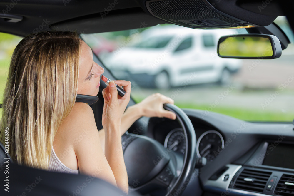 female driver talking on cellphone and applying lipstick female driver talking on cellphone and applying lipstick