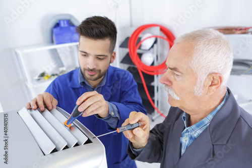 air conditioning repairmen discussing the problem with apprentice