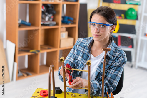 a woman cutting copper pipes photo