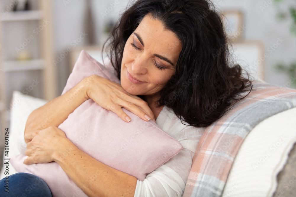 mature woman takes comfort cuddling a cushion mature woman takes comfort cuddling a cushion