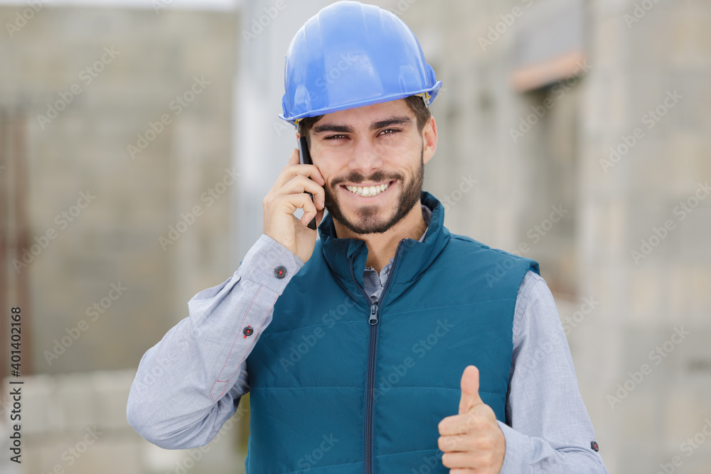 young constructor on the phone showing thumb up young constructor on the phone showing thumb up