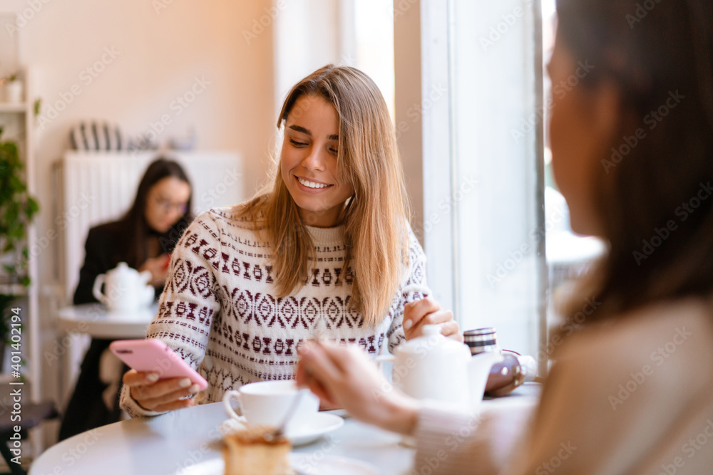 Two smiling young girlfriends using mobile phone Two smiling young girlfriends using mobile phone