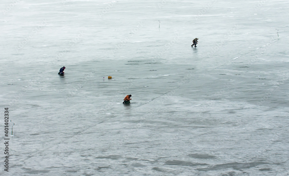 Winter fishing on a frozen lake. Lonely fishermen on the ice.