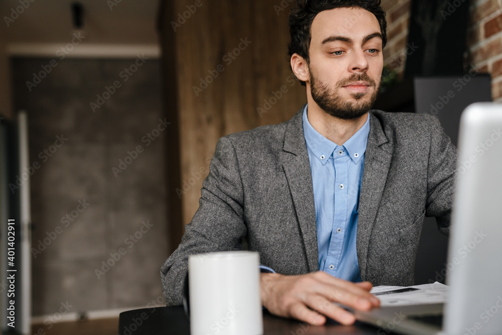 Handsome serious businessman using laptop while working at home Handsome serious businessman using laptop while working at home