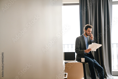 Wallpaper Mural Serious businessman talking on mobile phone while examining documents Torontodigital.ca